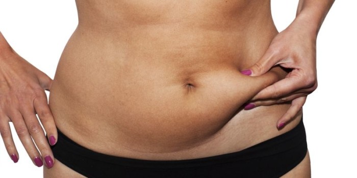 Woman's fingers measuring her belly fat