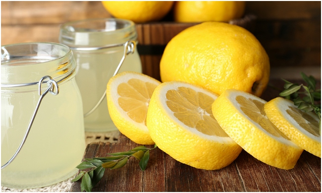 Still life with lemon juice and sliced lemons on wooden table, c