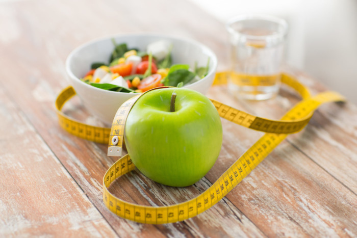 close up of green apple and measuring tape