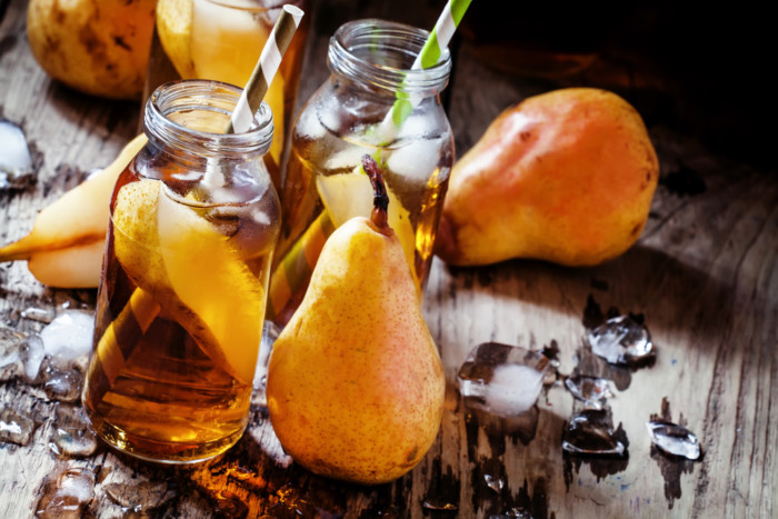 Cold pear juice with a straw, black background, selective focus