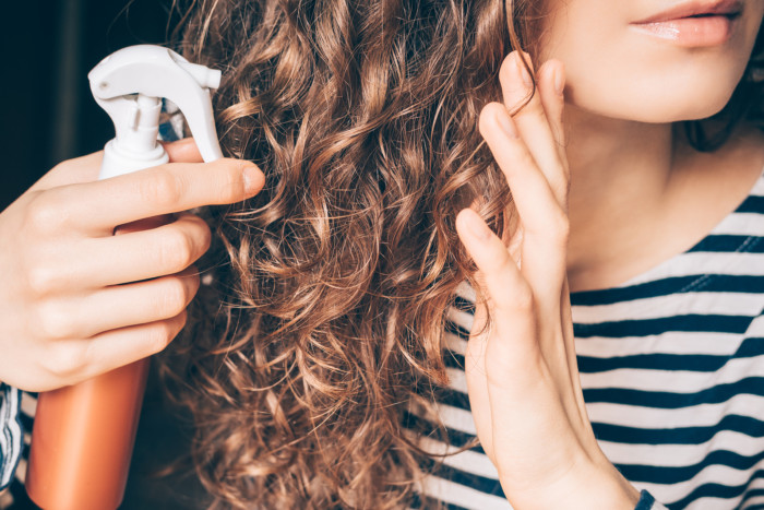 bigstock-Woman-Applying-Spray-On-Curly-197500345